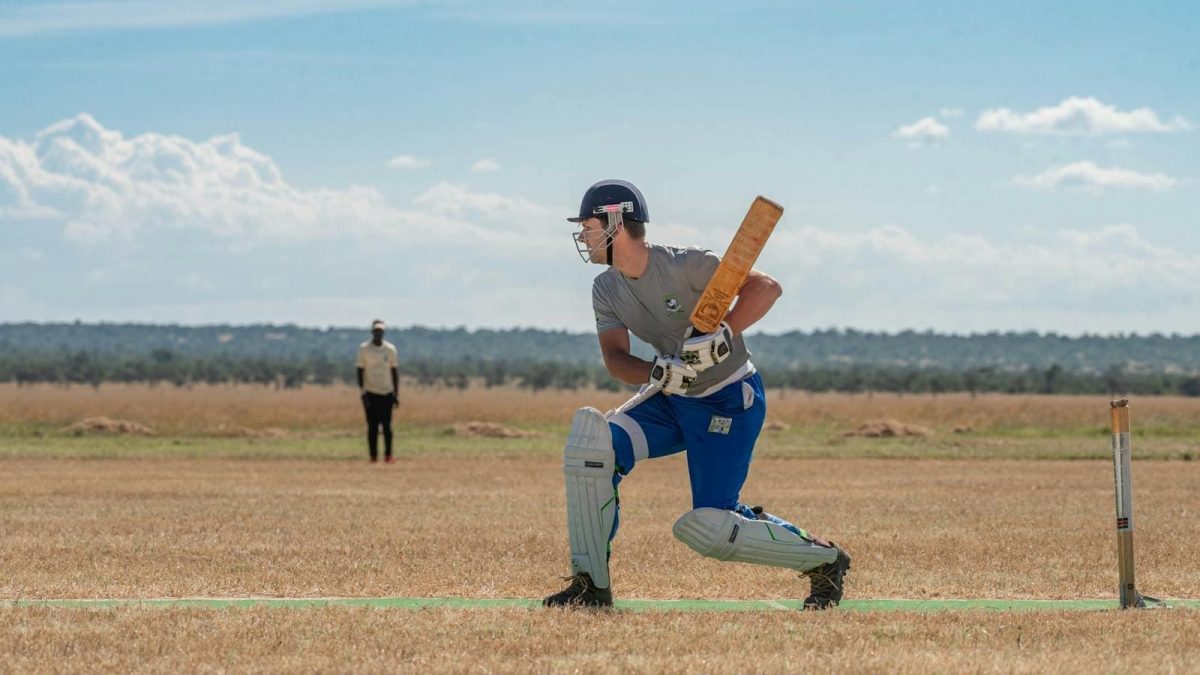 A man in blue and grey is playing cricket