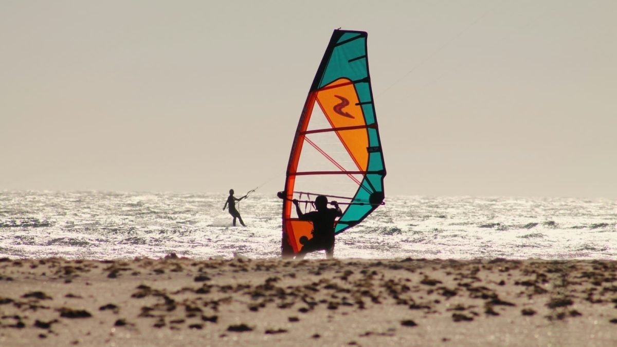 a man riding a wind sail on top of a sandy beach