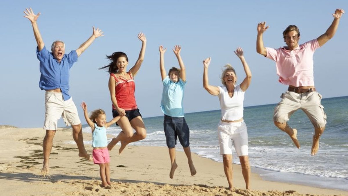 65656181 - portrait of three generation family on beach holiday jumping in air