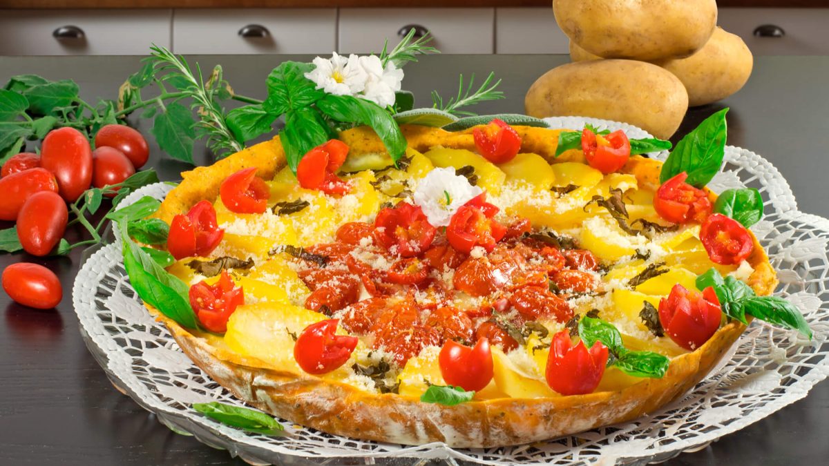 Tarte salée aux légumes dorée, découpée en parts sur une pâte brisée